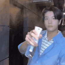 a young man in a blue jacket is holding a spray bottle in his hand .