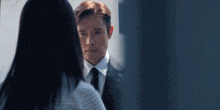 a man in a suit and tie looking at a woman