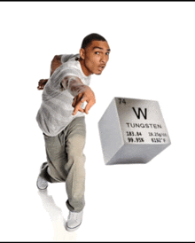 a man is pointing at a cube that says tungsten on it