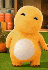 a yellow stuffed animal with a white belly is standing on a lush green field .