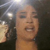 a woman with curly hair is singing with her mouth open