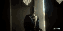 a young boy is standing in a dark room with a netflix logo in the corner