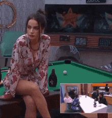 a woman is sitting on a pool table with a bottle of liquor in front of her