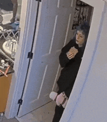 a woman is standing in a doorway in a bathroom holding a cup .