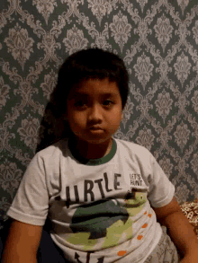 a young boy wearing a shirt that says " let 's hunt turtle "