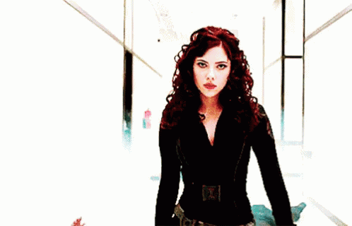 GIF of Black Widow casually maceing a guard who tried to approach her as she walks down a hallway