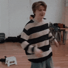 a man in a striped sweater is dancing in a room