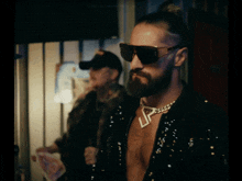 a man with a beard wearing sunglasses and a necklace that says lp