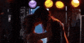 a man and a woman are standing next to each other on a stage under a row of lights .