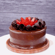 a chocolate cake with strawberries on top and chocolate curls