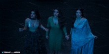 three women are standing next to each other in a dark room and the words pranay varma are on the bottom right