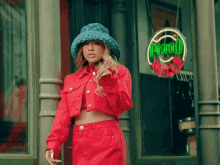 a woman in a red jacket and hat stands in front of a sign that says ' hollywood '