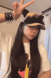 a girl wearing a hat and a bracelet with spikes is giving the peace sign