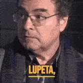 a man wearing glasses and a scarf says " lupeta " in yellow