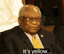 a man in a suit and tie with the words it 's yellow behind him