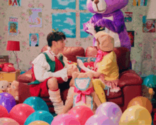 a man and a woman are sitting on a couch with balloons and a purple teddy bear
