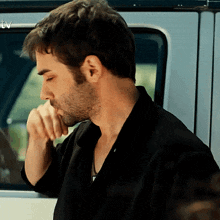 a man in a black shirt is sitting in a car with a tv logo in the corner