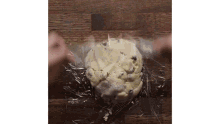 a person is wrapping a cookie dough in plastic wrap .