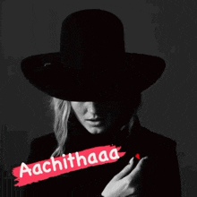 a woman wearing a black hat and a black jacket is holding a heart .