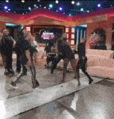 a group of people are dancing in a room with a couch and a sign that says ' champions ' on it
