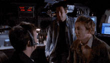 three men are standing in front of a computer monitor that says ' x-files ' on it