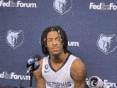 a basketball player is sitting in front of a microphone in front of a fedex forum wall .