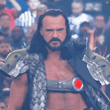 a man with long hair and a beard is wearing armor and a belt with a red circle on it