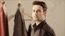 a man in a black shirt is standing in front of a row of clothes