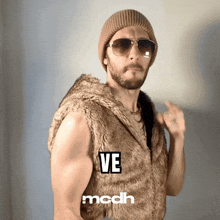 a man wearing sunglasses and a fur vest has the word ve on his chest