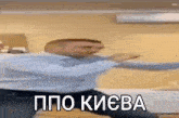 a man in a blue shirt is dancing in a room with a foreign language on his face .