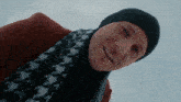 a man wearing a scarf and a hat is smiling for the camera