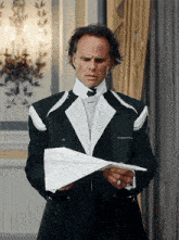 a man in a tuxedo is holding a paper airplane