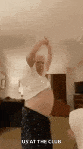 a man with a very large belly is dancing in a living room with his arms outstretched .