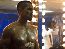 a shirtless man is standing in front of a mirror eating a cupcake