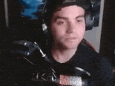 a man wearing headphones and a hat is talking into a microphone .