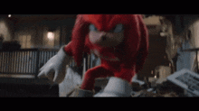 knuckles the echidna from sonic the hedgehog 2 is holding a red cloud in his hands and looking at the camera .