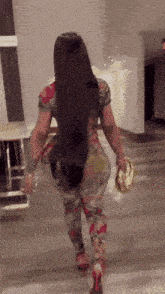 a woman with long hair is walking down a hallway holding a purse