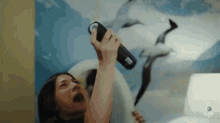 a woman is holding a flashlight in front of a painting of dolphins