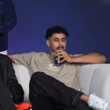 a man sitting on a couch drinking a glass of beer