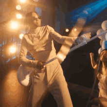 a man in a white suit playing a guitar