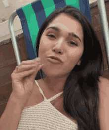 a woman is sitting in a beach chair holding a piece of food in her hand