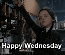 a girl in a black sweater is holding a telephone with the words `` happy wednesday '' written on it .