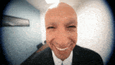 a bald man in a suit and tie is smiling for the camera