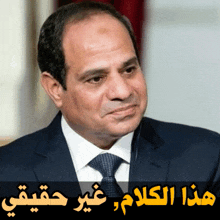 a man in a suit and tie stands in front of arabic writing