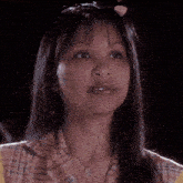 a close up of a woman 's face with a plaid shirt and a necklace