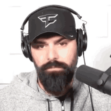 a man with a beard is wearing headphones and a hat with the letter e on it .