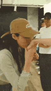 a woman wearing a hat is holding a man 's hand while standing in a room .