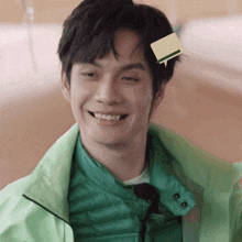 a man wearing a green jacket has a sticker on his head that says ' a ' on it