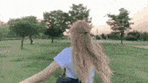 a woman is walking through a park with trees in the background .