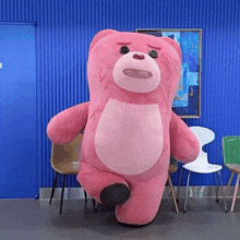 a large pink teddy bear is standing in a room